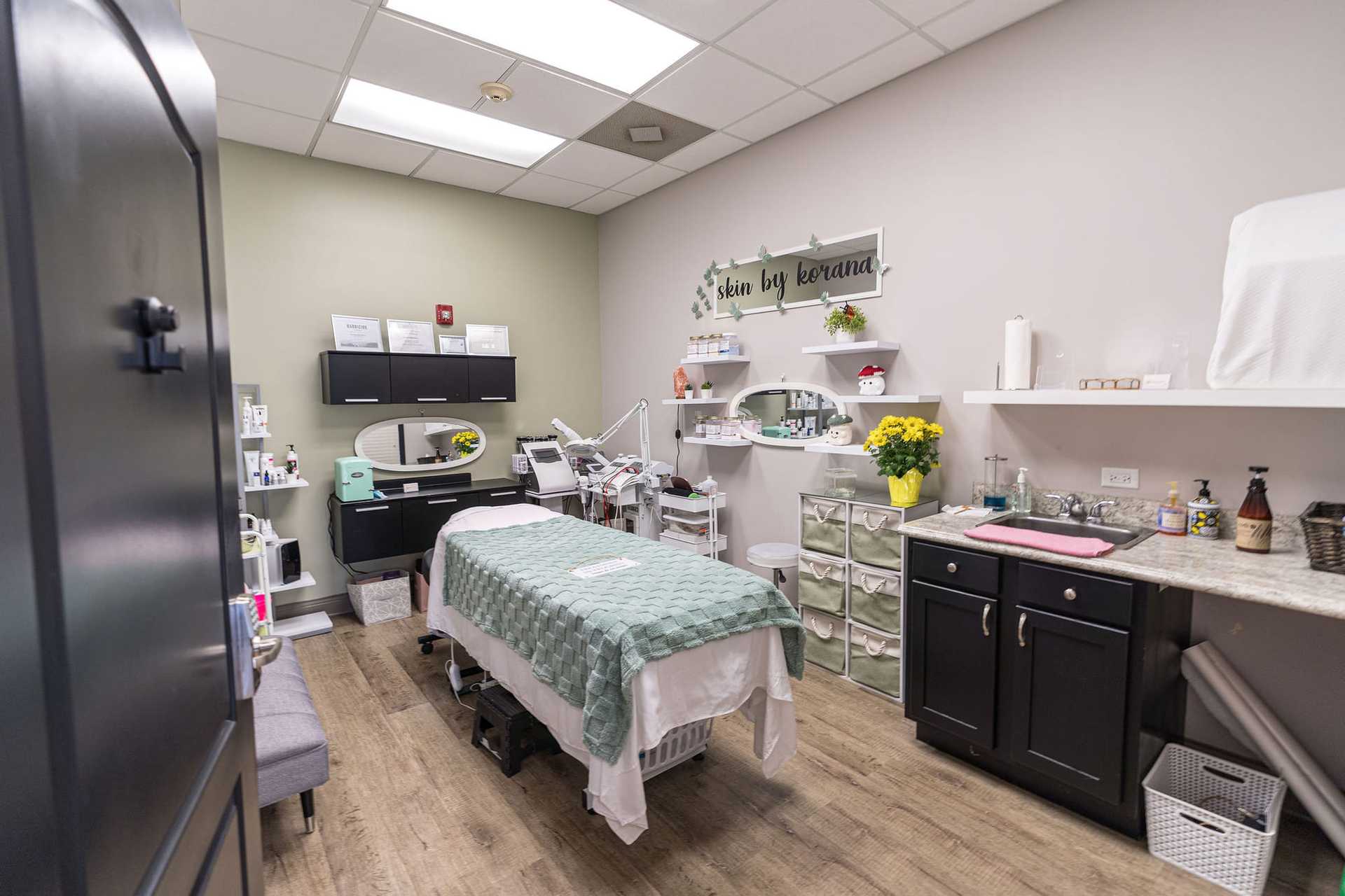 A well-organized medical spa treatment room with a padded bed, modern equipment, and soft lighting.