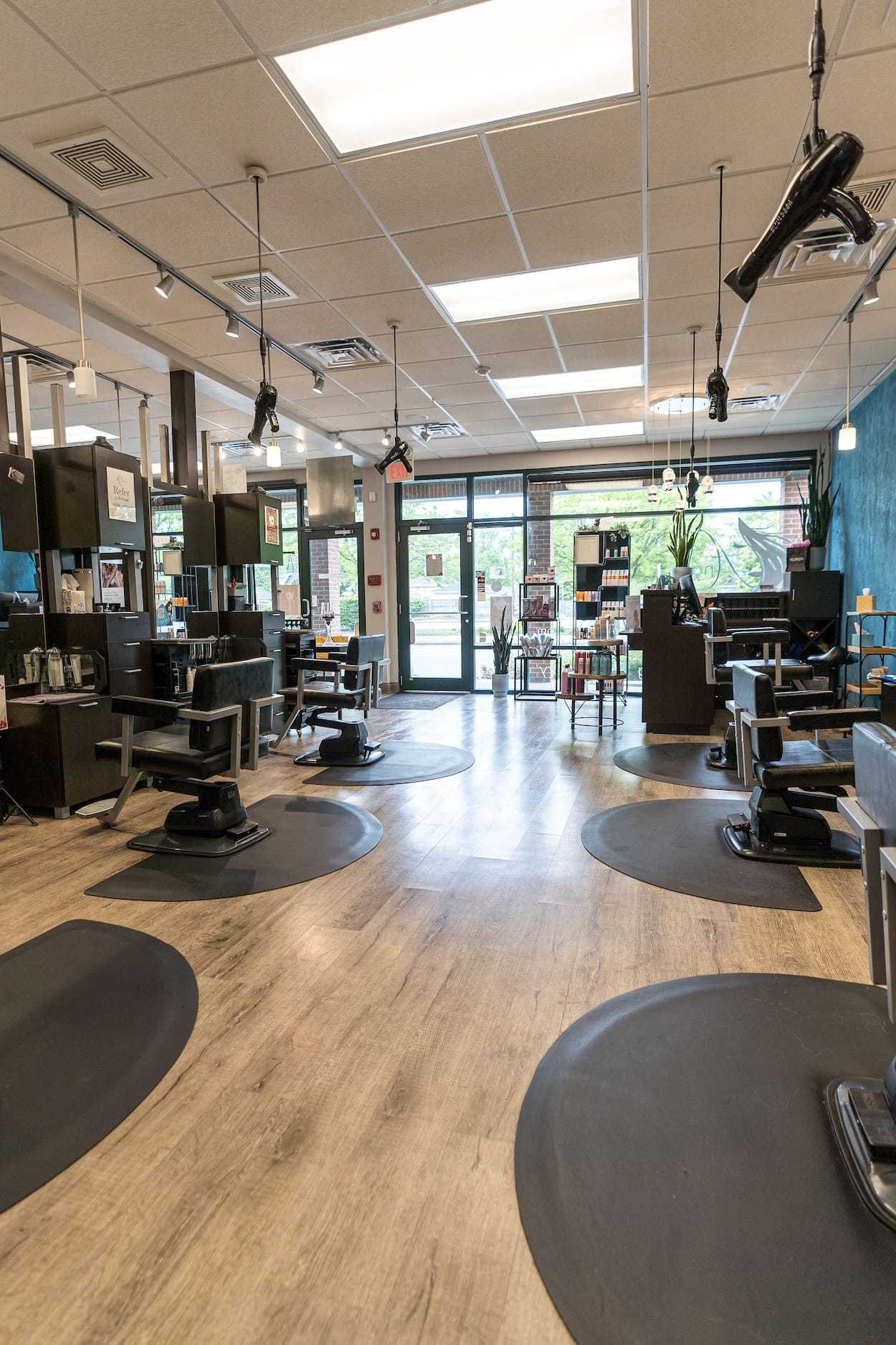Spacious modern hair salon with styling chairs, mirrors, and large front windows.