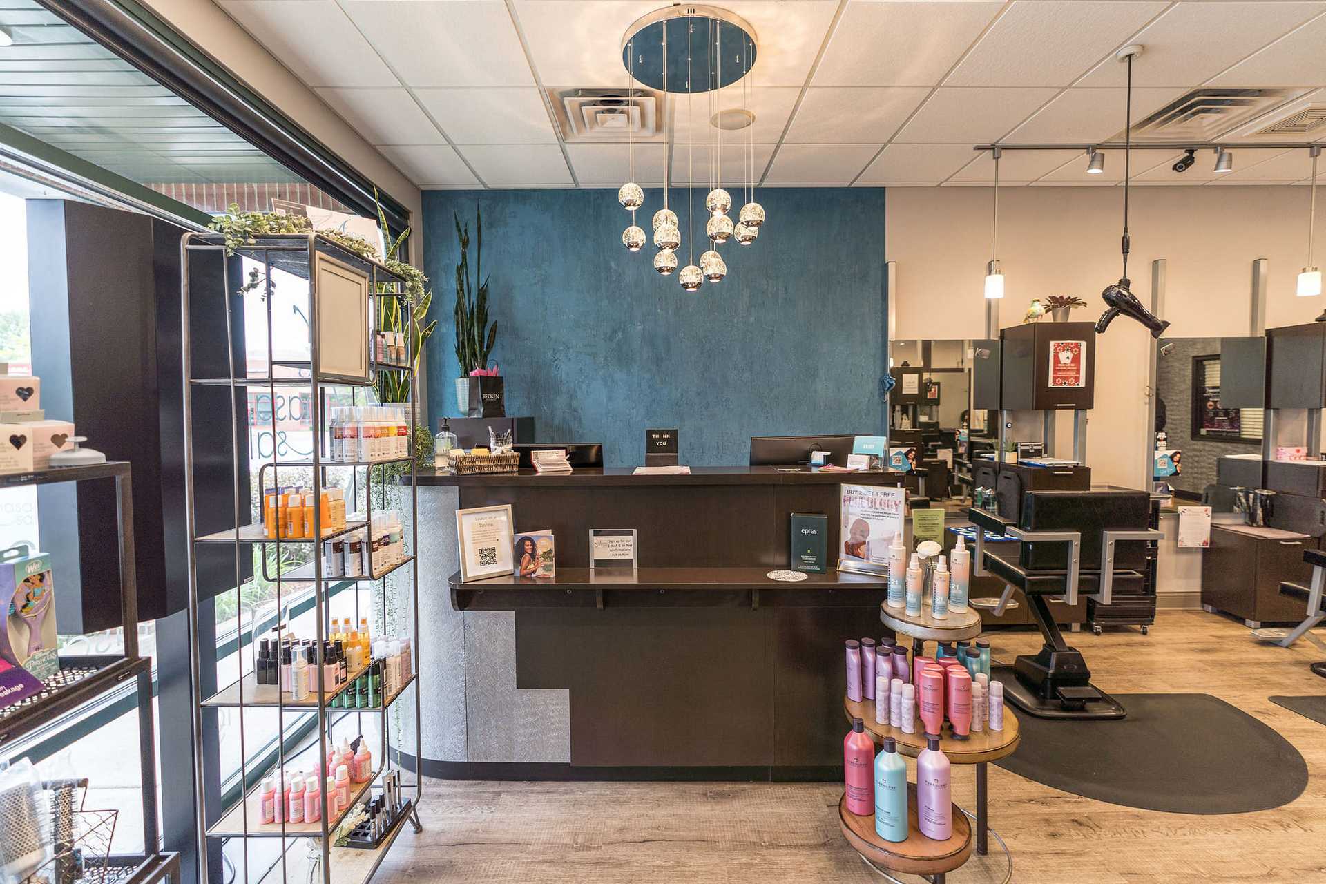 Modern salon reception area with shelving displaying hair products and front desk.