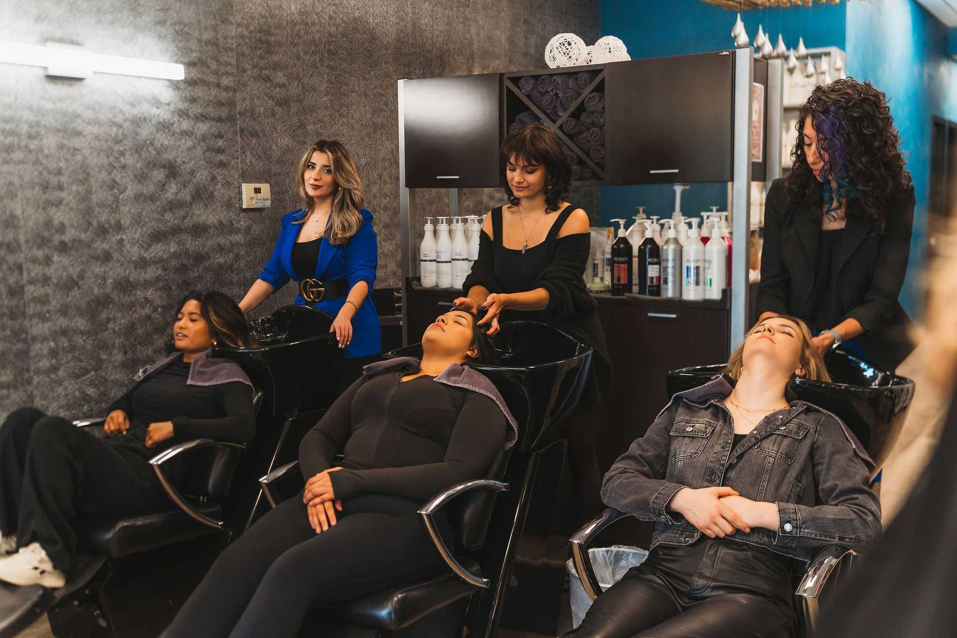 Women getting hair washed at a modern salon with stylists working attentively.